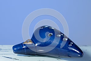 A blue ocarina in front of blue background photo