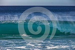 Blue ocean shorebreak wave front view