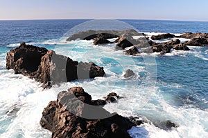 Blue ocean water crashing over rocks at a beach in Los Gigantes, Spain