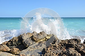 Blue ocean water splashing on rocks on the beach