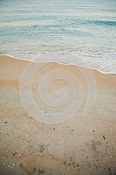 Blue ocean wave on sandy beach. Beautiful soft waves of the sea. Summer nature background. Sea shells are lying on the
