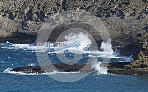 Blue ocean waves breaking on rocky coast