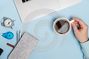 Blue Office desk of Business workplace. Woman hands with laptop, spectacles and coffee cup. Top view. Flat lay