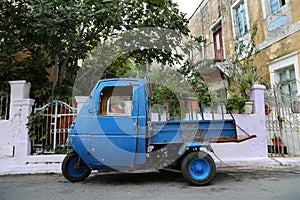 A blue old little pickup truck in the street by the old stone houses in Calymnos Island