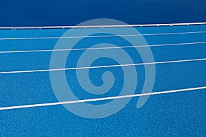 Blue Olympic track lanes with white stripes, an empty background suitable for copy space, represent the concept of physical sports