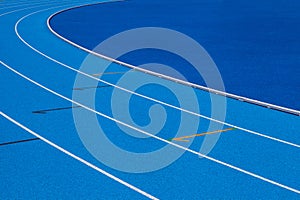 Blue Olympic track lanes with white stripes, an empty background suitable for copy space, represent the concept of physical sports