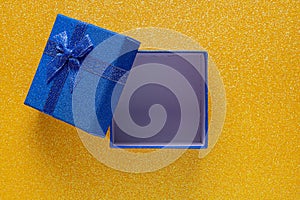 Blue open gift box on glitter yellow background with copy space. Top view. Xmas, Valentines day or birthday party concept.