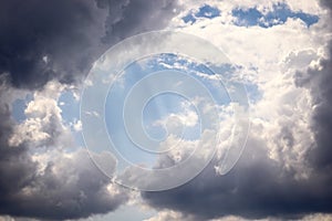 Blue open sky with dark and white clouds and light beams