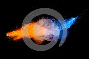 Blue orange color powder explosion cloud on black background. Closeup of Blue orange dust particles splash