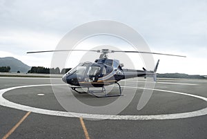 Blue and Orange Helicopter on Runway in Forested Area