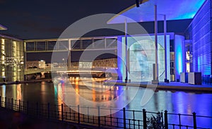 Blue and orange light effects of buildings and colored reflections in water of River Spree in Government District Berlin