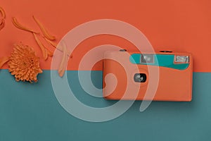 Blue orange plastic film camera and flower for summer traveling or vacation background