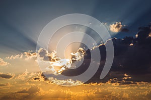 Blue and orange sky background with clouds and rays of sunset sun