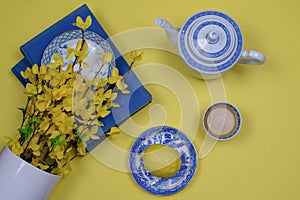 Blue oriental china dishes and vintage books on yellow background