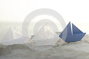 Blue origami boat wins the challenge on white boats, concept of success in business