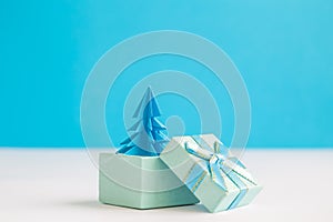 Blue origami christmas tree in form of present on table