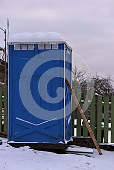 Blue outdoor toilet on inclined plaine with supporting construction to avoid falling it over.