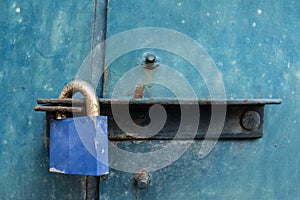 Blue padlock on steel door.