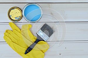 Blue paint in can, brush and yellow gloves