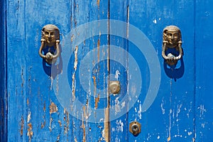 Blue painted aged wooden door with old bronze handles and locks in Rimini, Italy.