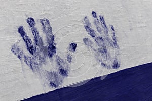 Blue painted hand print on white wall. Human hand, palm, fingers
