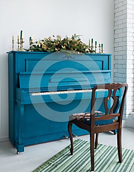 Blue painted old piano decorated with long Christmas garland