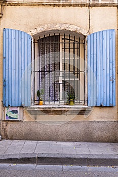 Blue painted shutters on an iron barred window