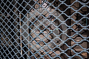 Blue painted wavy patterned gratings in front of glass window with blurry abstract reflection in it. Architectural details