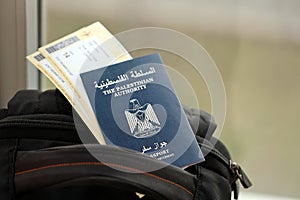 Blue Palestinian Authority passport with airline tickets on touristic backpack close up