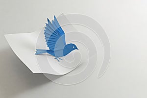 The blue paper bird breaks out of the sheet. Space for text. photo