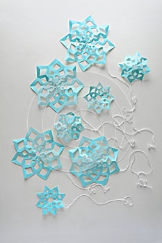 Blue paper snowflakes balloons with threads laying on white background. Top view. Christmas decoration