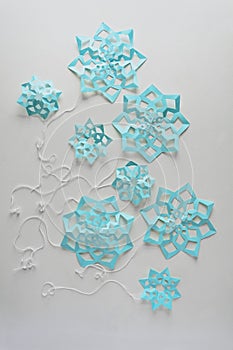 Blue paper snowflakes balloons with threads laying on white background. Top view. Christmas decoration. Toned