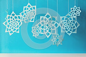 Blue paper snowflakes hang on threads on paper background. Top view. Christmas decoration. Toned