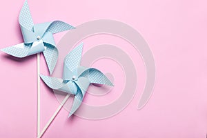 Blue paper spinners on light pink background. Kids toys colorful pinwheels on celebration party background. Top view, flat lay