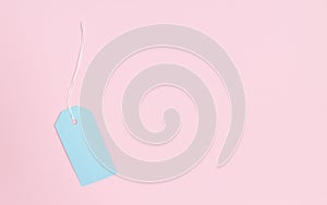 Blue paper tag for notes on a pink background. View from above.