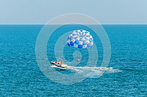 Blue parasail wing pulled by a boat in the sea water, Parasailing also known as parascending or parakiting