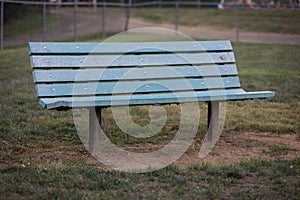 Blue park bench in park with fence behind it