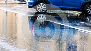 Blue parked car outdoors with reflect in wet asphalt