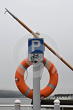 Blue parking sign for cars and bicycles on a signpost with an orange life buoy