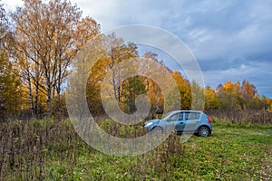 A blue passenger car on the background of grass and autumn forest