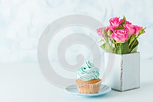 Blue pastel horizontal banner with decorated with cream cupcake and pink roses in retro shabby chic vase.