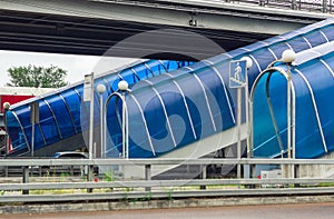 Blue pedestrian tunnel bridge over a highway with multiple exits in the city on traffic interchange