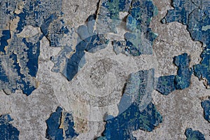 Blue peeling paint on the wall. Old concrete wall with cracked flaking paint.