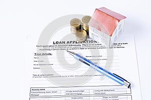 Blue pen with coins stack and house paper on loan application