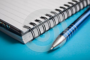 Blue pen on spirales notebook on blue background
