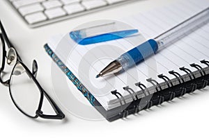 blue pen on spirales notebook on white desk background