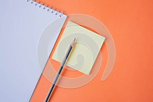 Pencil and notepad on orange background