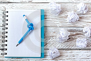 Blue Pencil with knot on writing pad on white wood background