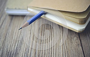 Blue pencil log the blank book on wooden in vintage tone