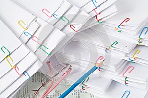 Blue pencil with spectacles put on stack of overload paper